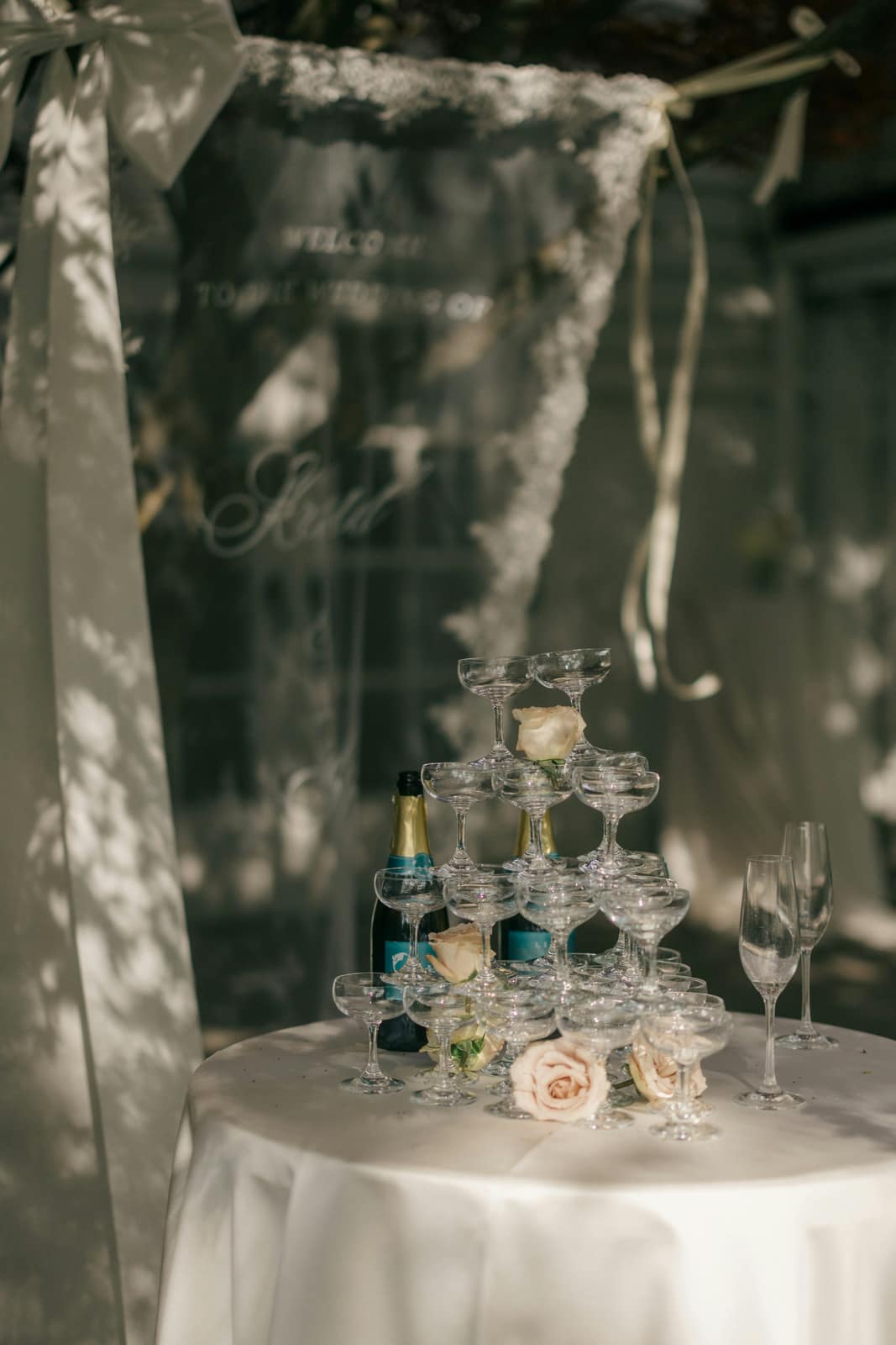 A welcome sign and champagne coupes seen through a veil